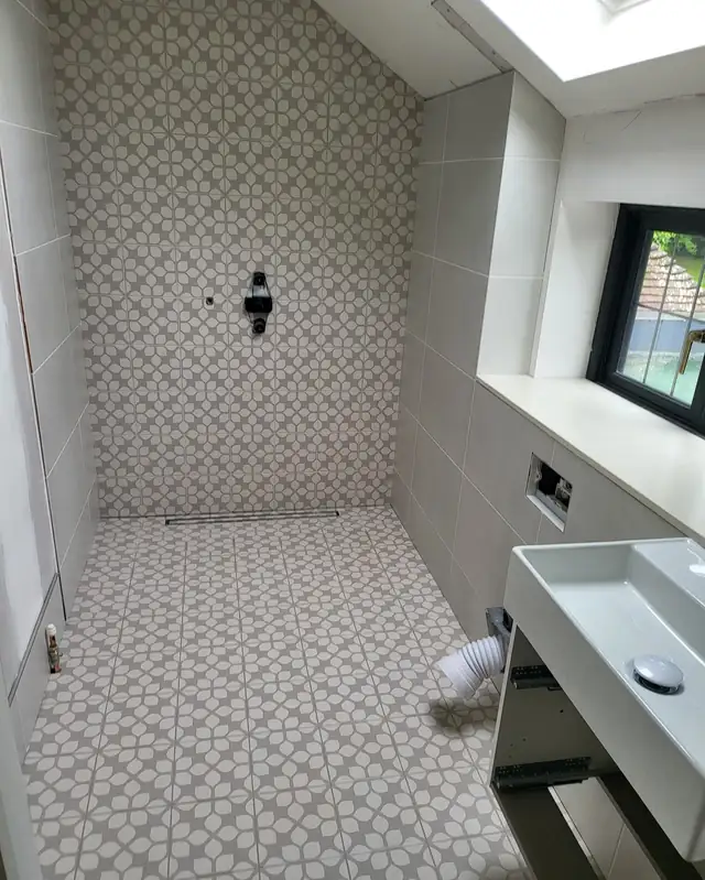 Shower room with patterned grey and white tiles on the floor and back wall
